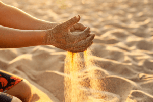 child's hands playing in the sand