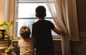 two kids looking out a window