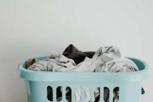 picture of an aqua colored laundry basket overflowing with clothes