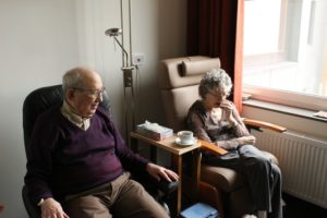 elderly couple sitting side by side in a residential care facility