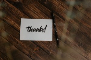 picture of a thank you card that says "thanks!" on a wood floor with a pen