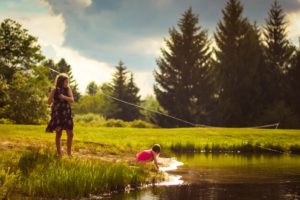 one girl fishing the other leaning over the water