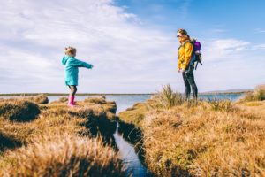 little girl and mom facing each other outdoor in nature near water