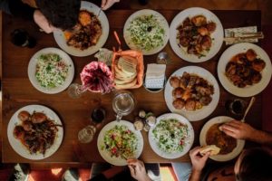 above photo of a table filled with food with multiple people eating