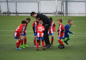 picture of a team of young soccer players and their coach on the field in a huddle