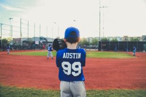 picture of the back of a boy on a baseball field getting ready to pitch a ball