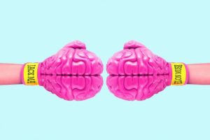 picture of two boxing gloves that look like pink brains facing each other