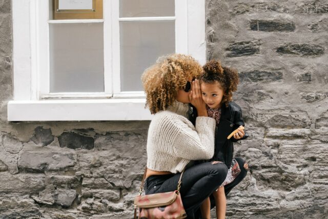 mom whispering in daughter's ear
