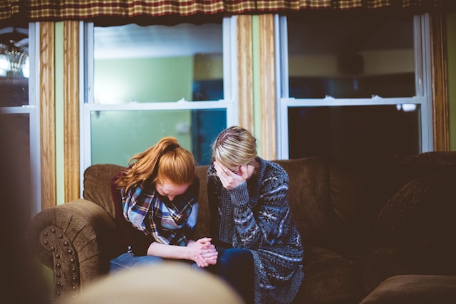 two friends crying together on couch