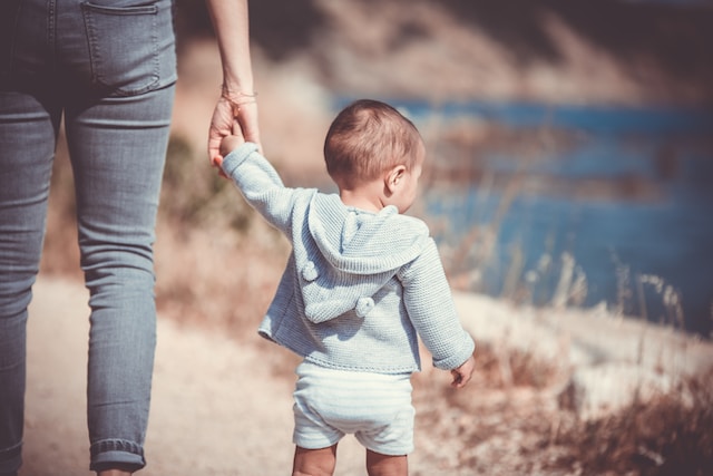 mother holding toddler's hand on beach