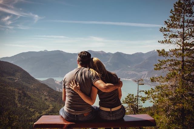 couple sitting on bench together looking at mountain view