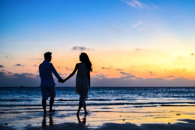couple walking on beach at sunset