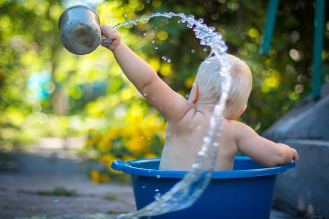 baby playing with water in bucket