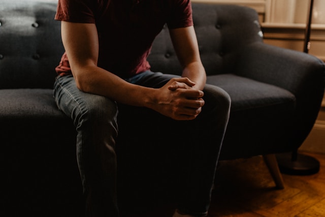 man sitting on couch with hands in lap