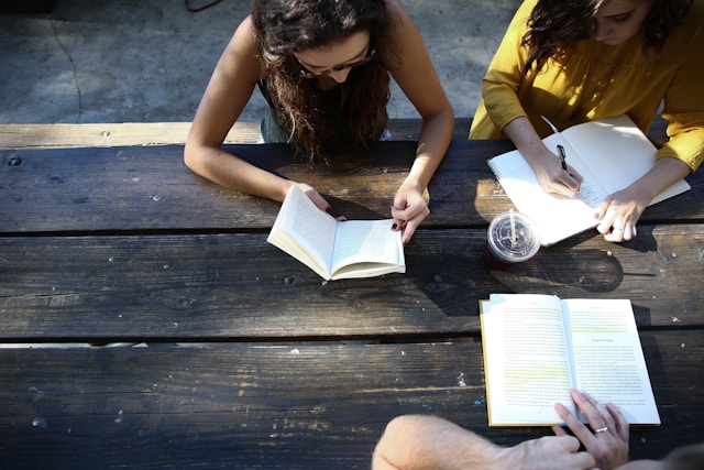 teens sitting at a picnic table looking at books