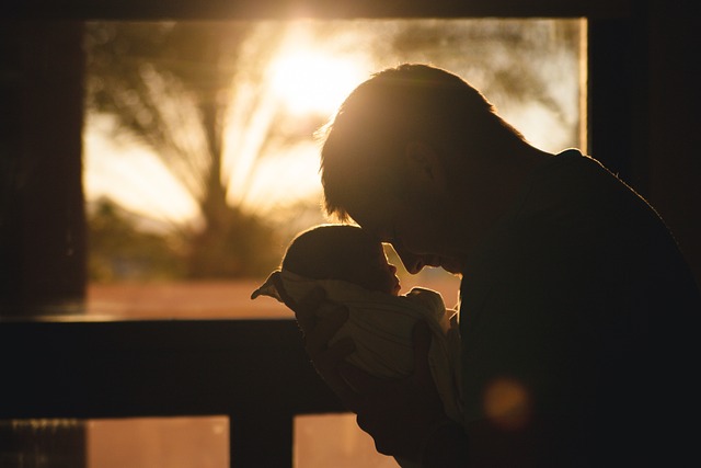 father cradling newborn at sunset 