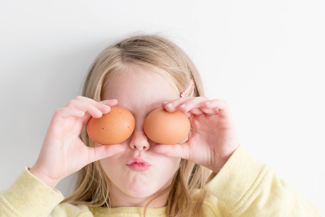 girl holding eggs over eyes