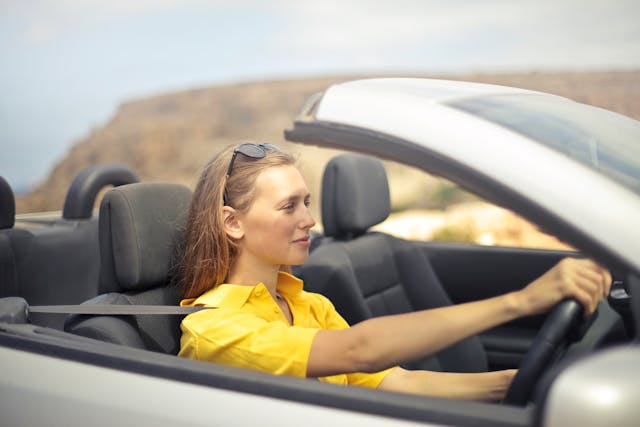 girl in yellow driving convertible
