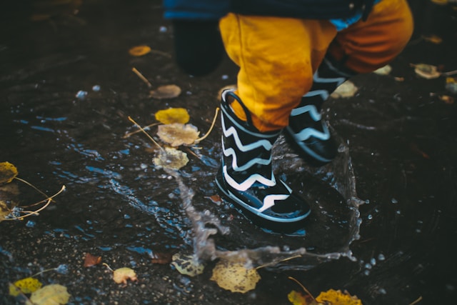 young child splashing in rain puddle