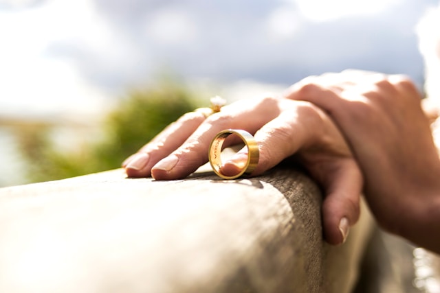 woman's hand holding both wedding rings