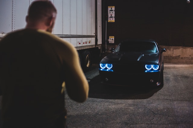 man walking towards car at night
