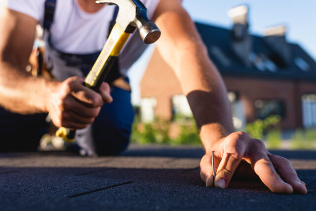 guy hammering nails on roof