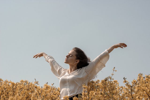 woman with hands open wide in field