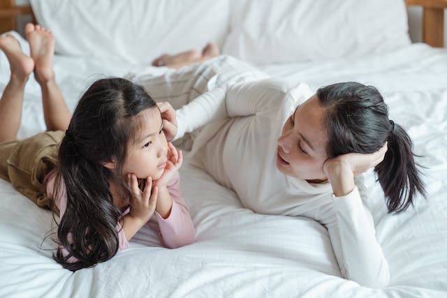 mom talking to daughter on bed