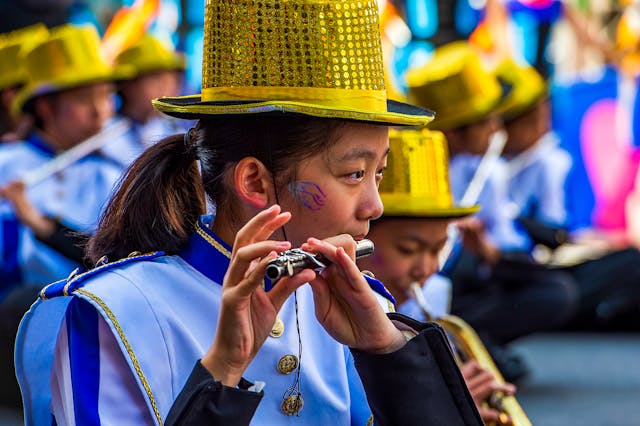 girl playing flute wearing gold hat