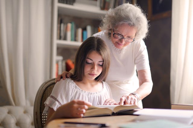senior woman helping young girl read