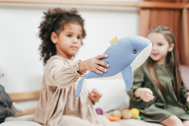 little girl playing with stuffed whale