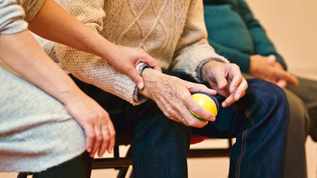 caregiver squeezing arm of senior man holding lemon