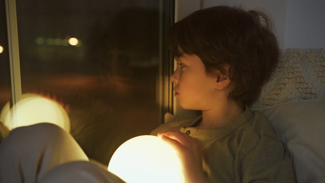 boy looking out window at night