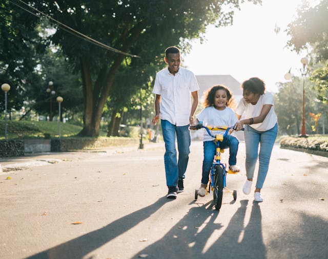 family teaching daughter to ride bike