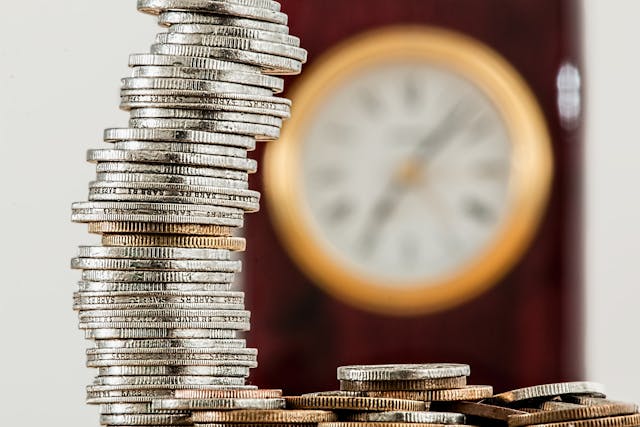 coins stacked in front of clock