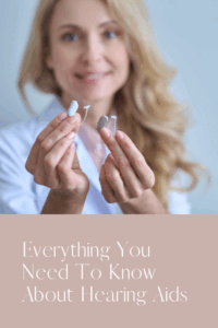 a young woman holding up hearing aids