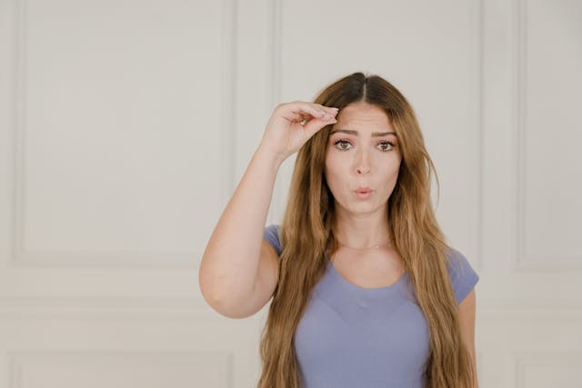 a young woman holding up a hearing aid