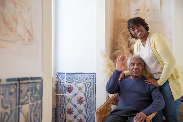 happy senior couple waving by window
