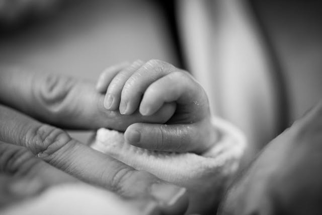 newborn baby's hand holding parents hand