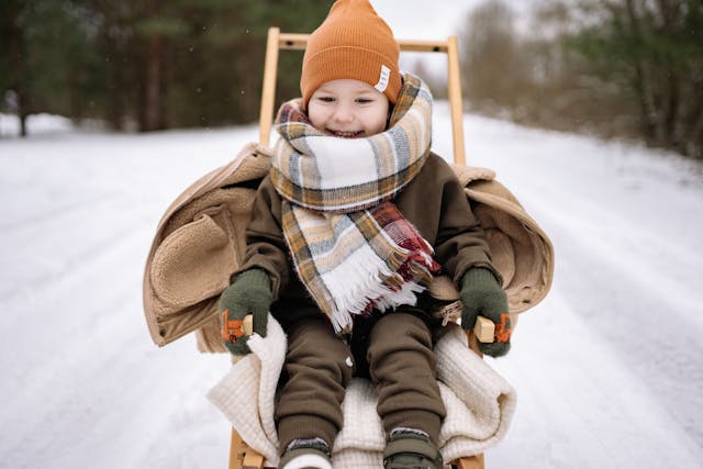child bundled up in sled out in snow