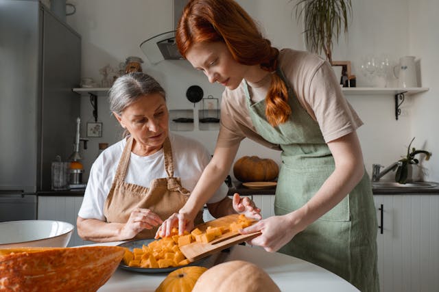 young woman helping older woman in kitchen