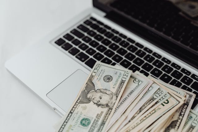 laptop with money on top of it