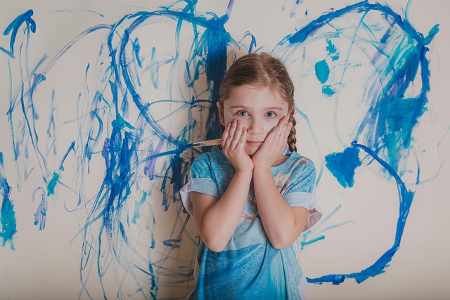 girl with hands on face in front of blue paint