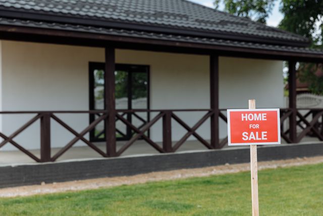 house with red house for sale sign in front of it