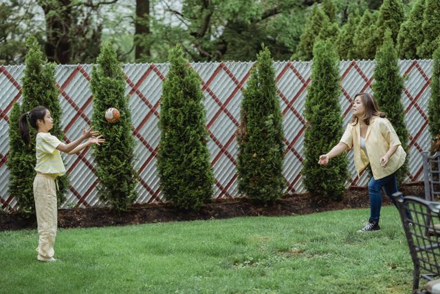 mom and daughter tossing ball in the backyard