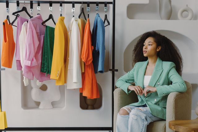 stylish woman sitting by clothing rack