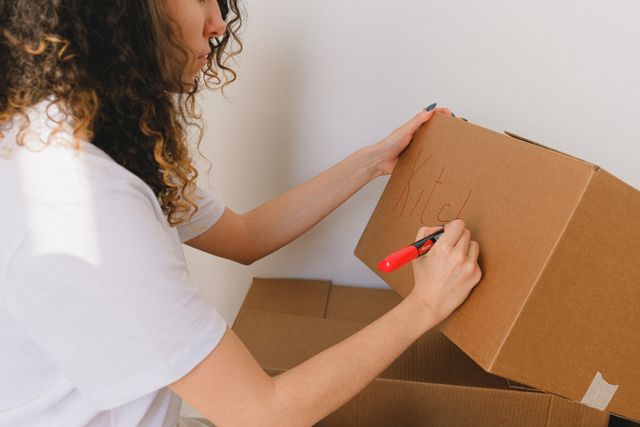 woman writing on moving box