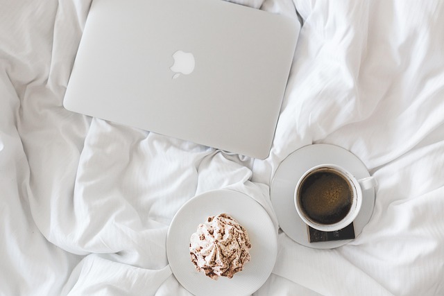 laptop and cup of coffee on bed