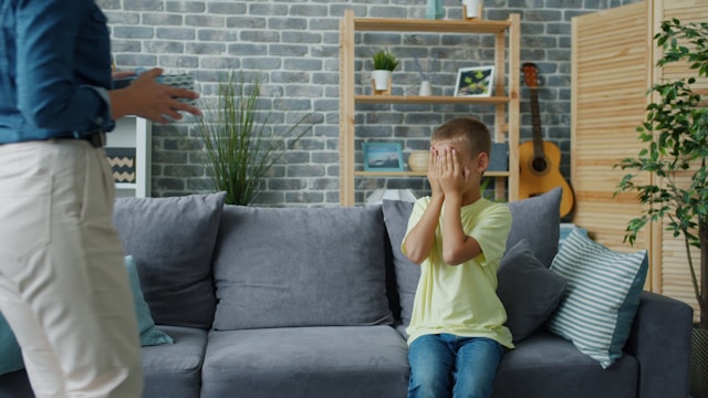 upset boy on couch covering eyes