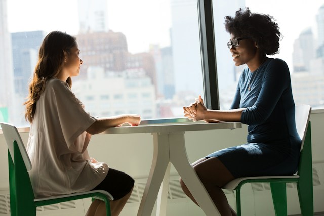 two woman talking at table